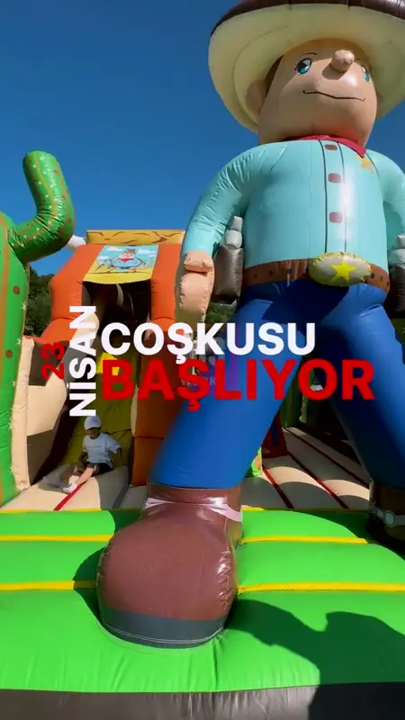 A child sliding down a giant cowboy-themed inflatable play structure