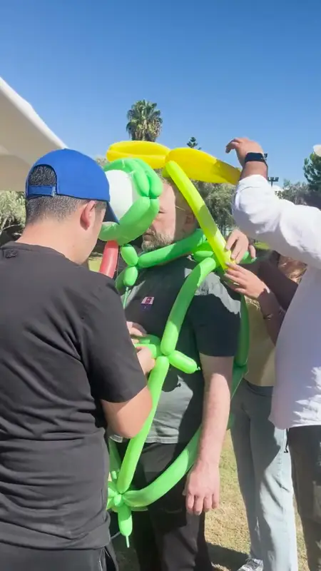 Bahçede takım arkadaşını yeşil ve sarı model balonlardan bir kostümle giydiren ekip