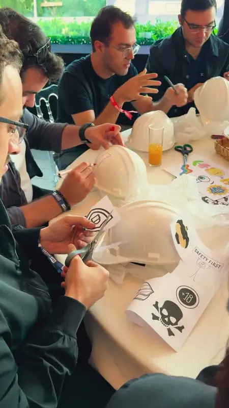 Participants decorating white hard hats with pens and stickers at a round table