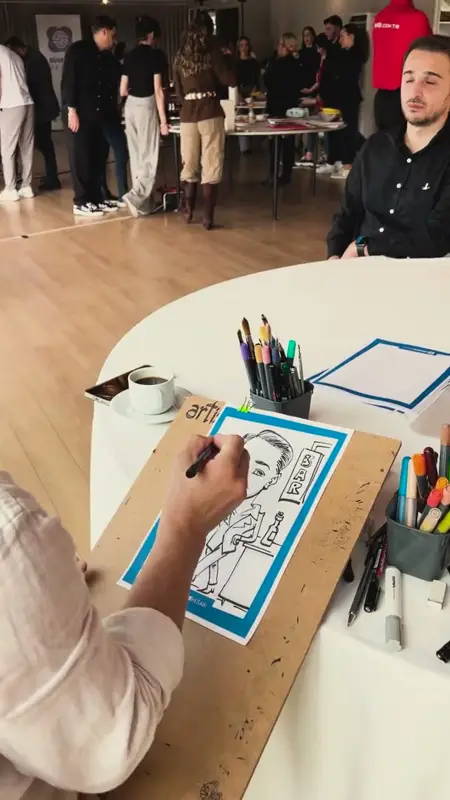 Karikatüristin keçeli kalemle bir katılımcının karikatürünü çizmesi
