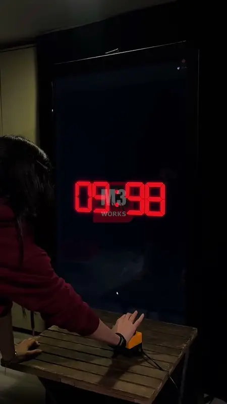 Karanlık alanda dev kırmızı LED sayaç 9.98 gösterirken butona basan oyuncu