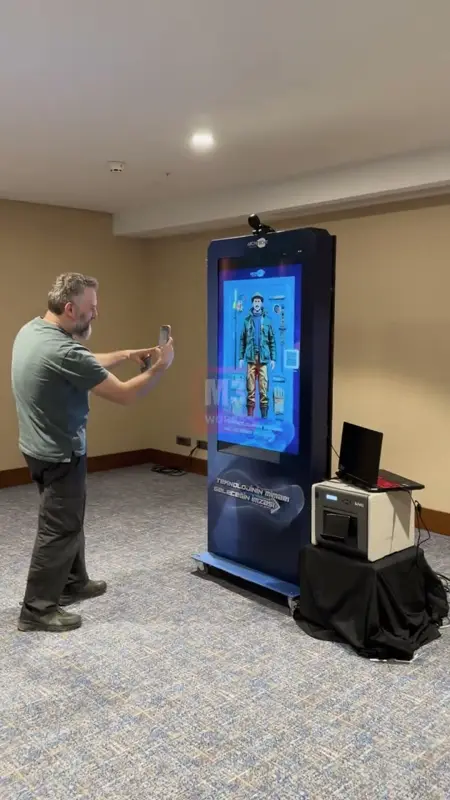 Otel etkinlik katında kameralı fotoğraf kioskunun önünde telefonla çekim yapan ziyaretçi