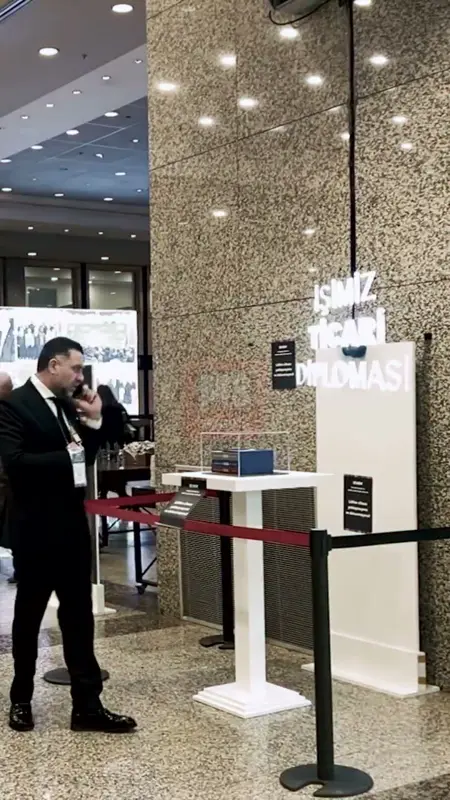 Kongre fuayesinde beyaz kaideler üzerinde havada süzülen hologram yazısı