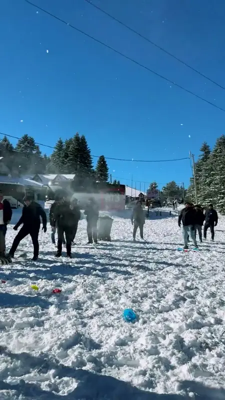 Participants throwing snowballs in a sunny snowy field with coloured markers on the ground