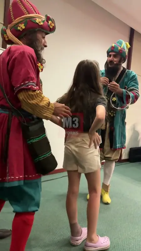 A girl invited on stage with actors in Karagöz and Hacivat costumes