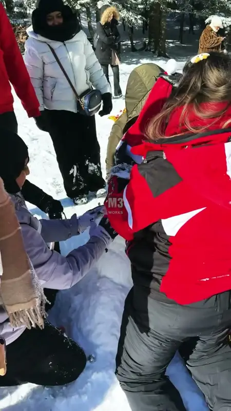 Karda diz çökerek kardan adamın gövdesini şekillendiren takım üyeleri