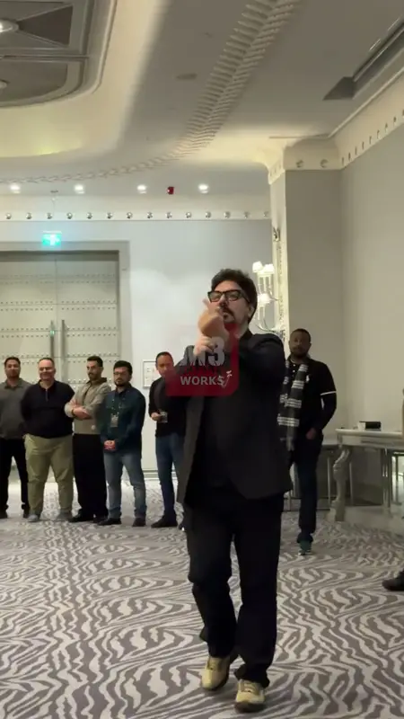 Otel salonunda takımlara talimat veren sunucu ve onu dinleyen katılımcılar