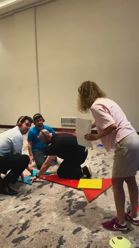 Kulaklık takan oyuncuların yerde dev tangram parçalarını birleştirmesi
