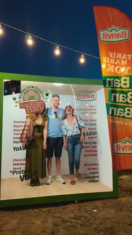 Açık havada dev dergi kapağı dekorunun içinde poz veren üç misafir
