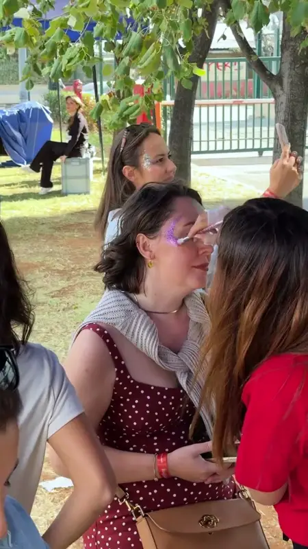 A makeup artist applying glitter around a guest's eyes