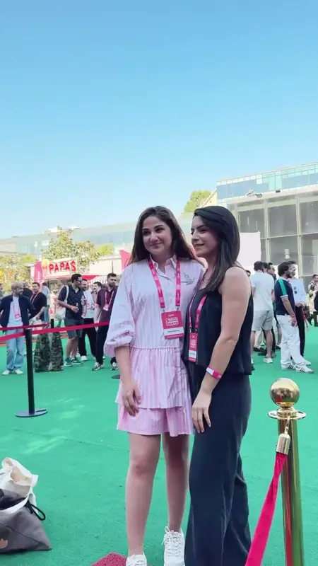 Two guests posing side by side on the red carpet