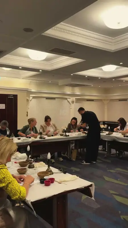Otel salonunda uzun masalarda mozaik lamba yapan katılımcılar