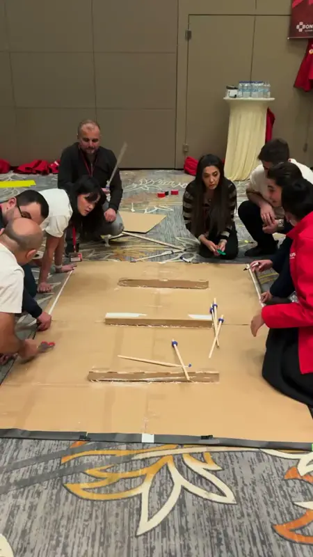 A team fitting stick braces to a cardboard bridge section