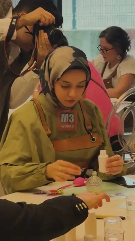 Önlüklü katılımcı masada esans şişesiyle karışımını hazırlıyor