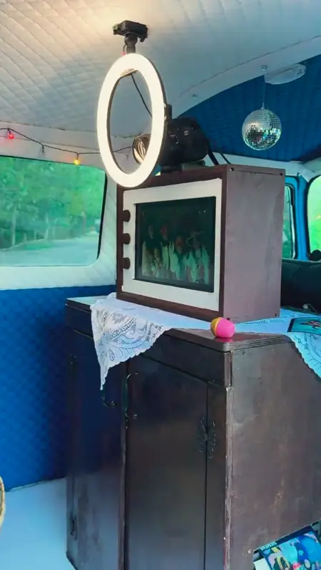 Camera with a ring light and a preview screen in a wooden cabinet inside the photo bus