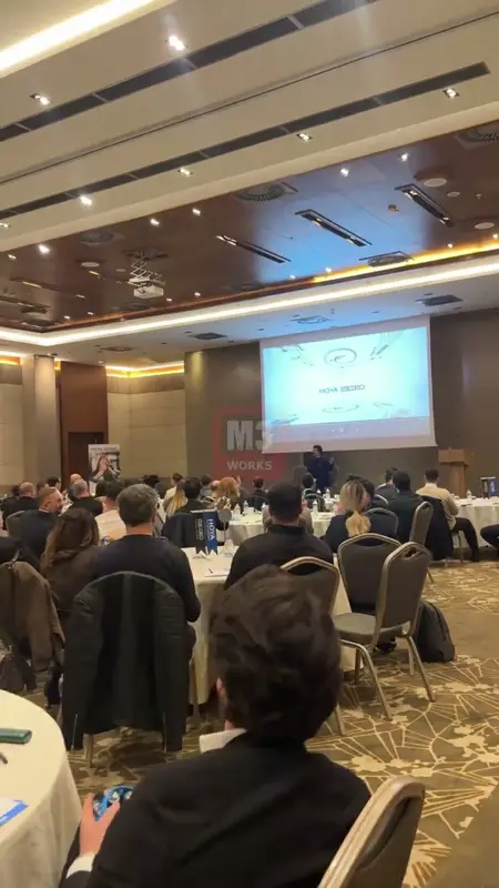 Participants at round tables in a hotel ballroom with the rhythm facilitator on stage