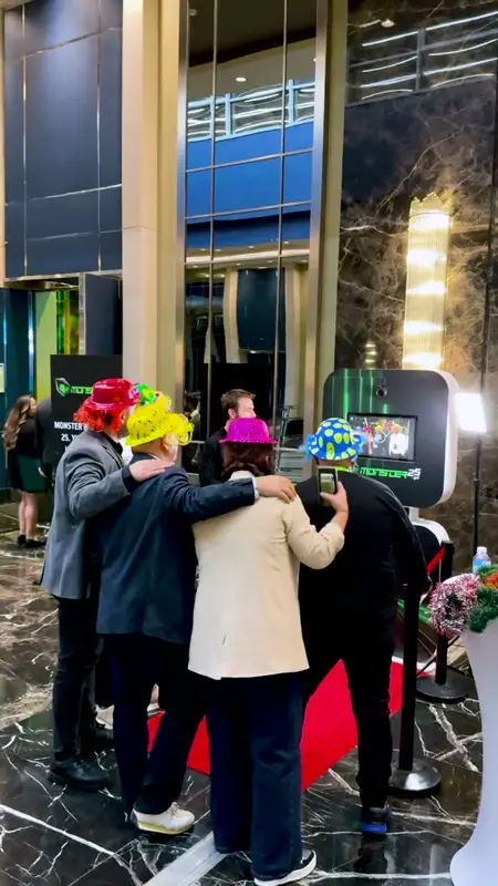 Guests with props posing at a branded selfie booth in a marble-floored lobby