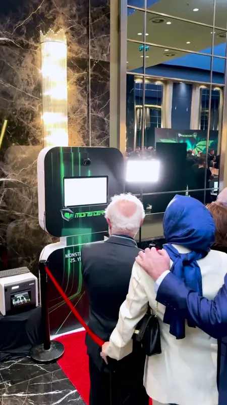 Kırmızı halıda markalı selfie booth karşısında poz veren misafirler