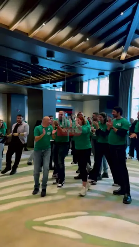 Participants in green shirts clapping to support their team in the hall