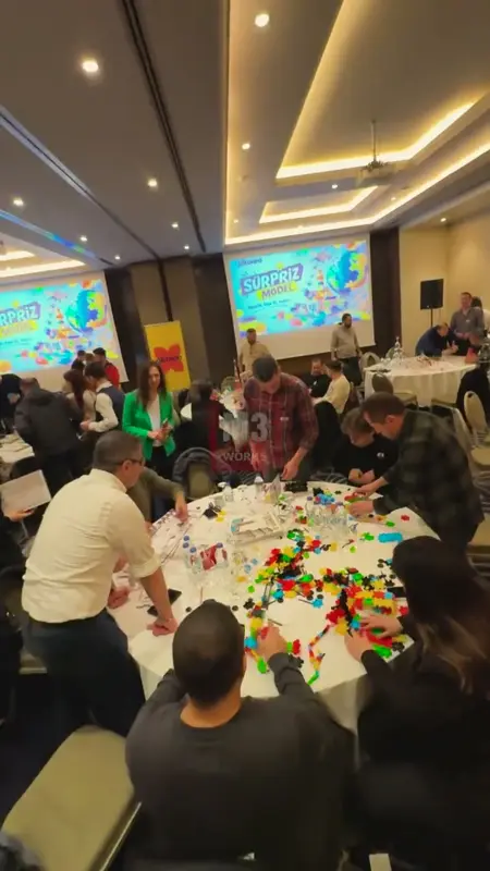 Kalabalık otel salonunda masalar etrafında maket üreten takımlar