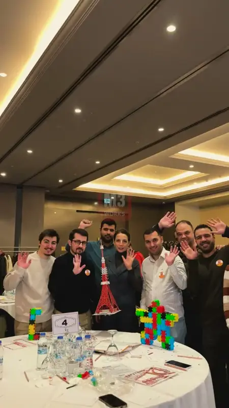 Otel salonunda masadaki renkli maketleriyle poz veren takım