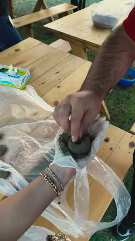 Dark seed ball being rolled in a gloved palm