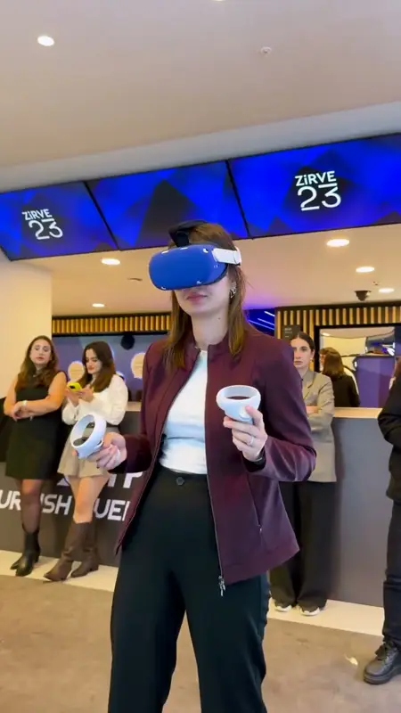 Etkinlik alanında VR gözlüğü ve kontrolcülerle oyun oynayan kadın katılımcı